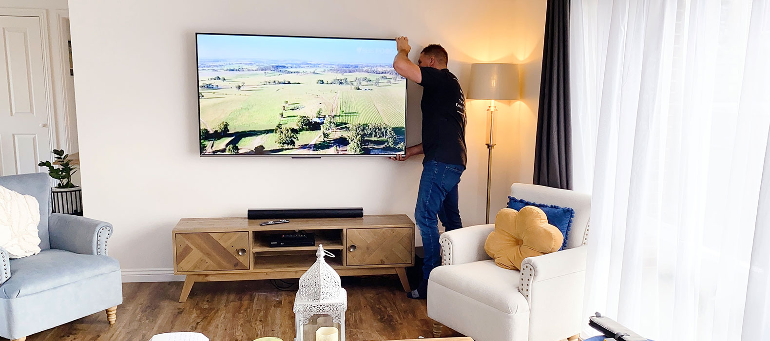 A man standing in front of a tv holding something up to the wall.