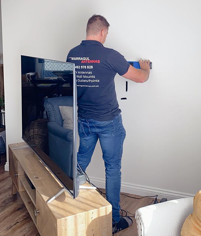 A man is working on the wall of his tv.