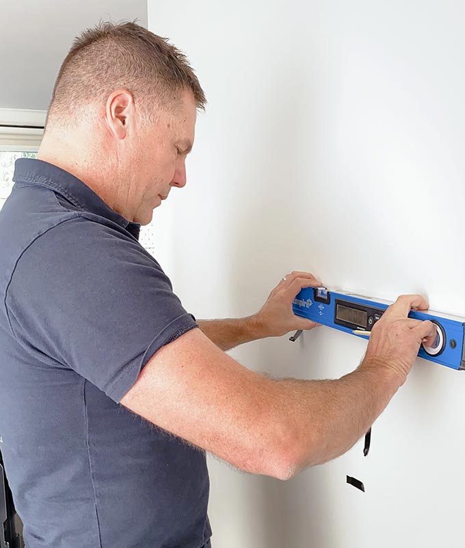 A man is working on the wall of his home.